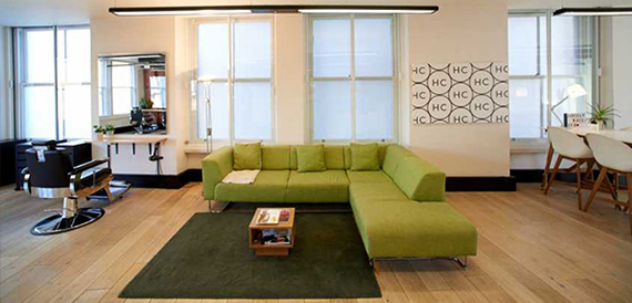 Lounge with a green corner sofa, barber chair and patterned wall artwork