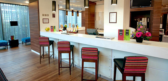 Bar counter with striped stools, bottled drinks and a small flower display.