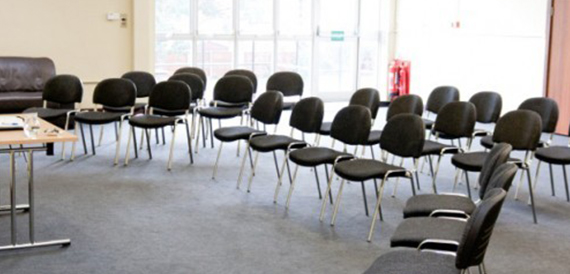 Rows of black chairs arranged in a semi-circle facing glass doors