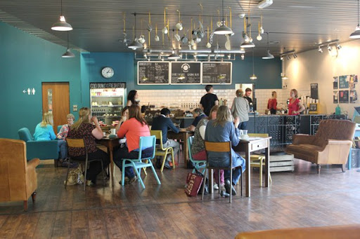 Cafe interior with teal walls, hanging pendant lights and a chalkboard menu