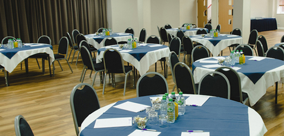 Function room set with round tables in blue linen on a wooden floor