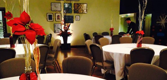 Dining room with round tables and tall red floral centrepieces