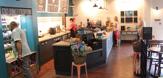 Cafe counter with staff serving customers beneath chalkboard menu boards