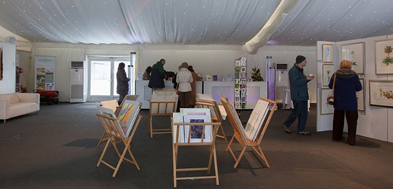 Exhibition space with deckchairs displaying artwork and visitors browsing the pieces
