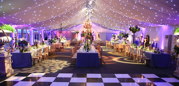 Marquee wedding reception with purple lighting, long tables and a checkerboard dance floor
