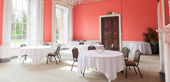 Coral-walled reception room with round tables set for a break