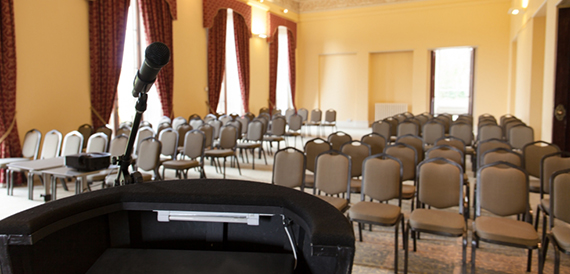 View from a lectern over rows of chairs in a yellow-walled hall