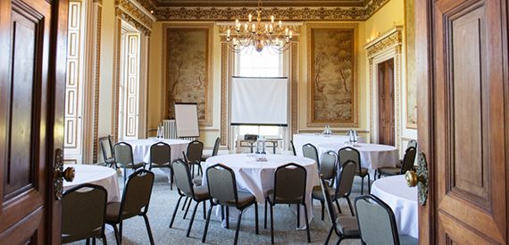 Cabaret round tables viewed through open doors beneath a chandelier