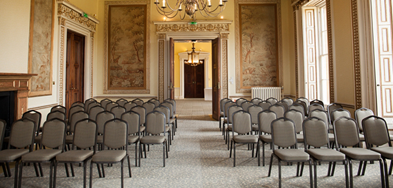Theatre-style seating in a period room with ornate wall panels and a chandelier