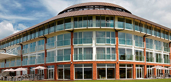 Curved modern hotel exterior with balconies and a terrace below