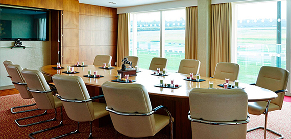 Boardroom with an oval table, cream leather chairs and racecourse views