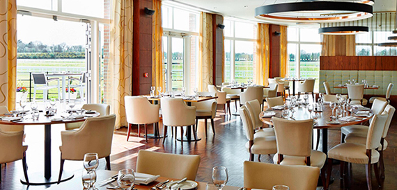 Restaurant with cream chairs and round pendant lights overlooking the countryside