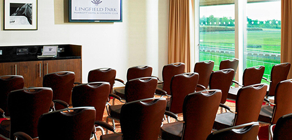 Theatre-style seating facing a screen with racecourse views through the window