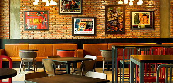 Bar area with an exposed brick wall, vintage film posters and tan booth seating
