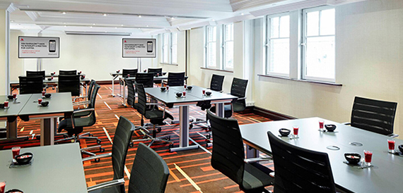 Meeting room set classroom-style with grey tables and black swivel chairs