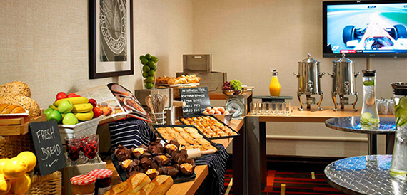 Breakfast buffet spread of fresh bread, fruit and pastries beside a television