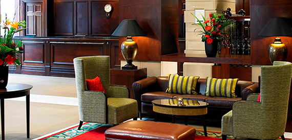 Hotel lobby lounge with green wingback chairs and a brown leather sofa