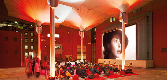Canopy-covered courtyard set up for an outdoor screening with cushioned seating.