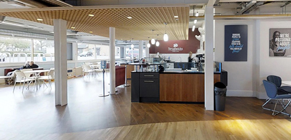Breakout area with a coffee bar counter and white cafe-style tables and chairs.