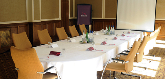 Boardroom with a long table, orange chairs and a projector screen.