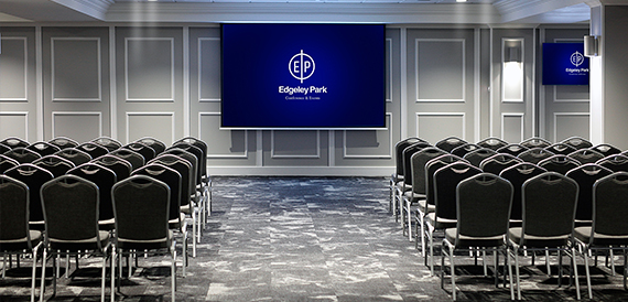 Theatre-style meeting room with rows of black chairs facing a branded presentation screen.