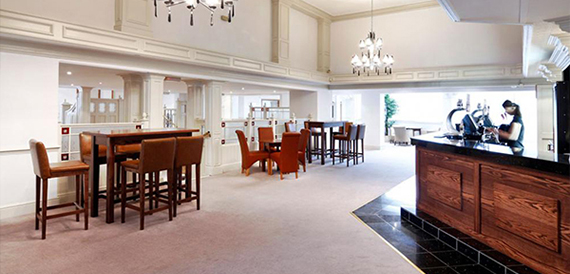 Bar area with high tables, leather chairs and a dark wood counter.