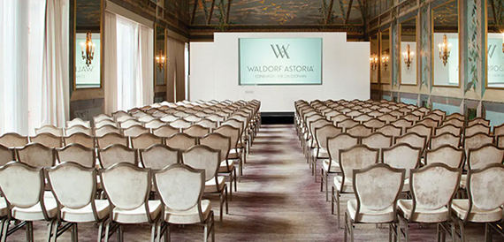Conference room set theatre-style with cream chairs facing a screen
