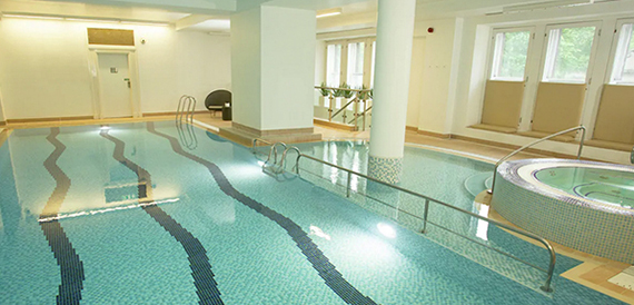 Indoor swimming pool with a jacuzzi and mosaic tiled surrounds