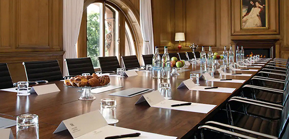 Boardroom with a long table and dark chairs beside an arched window