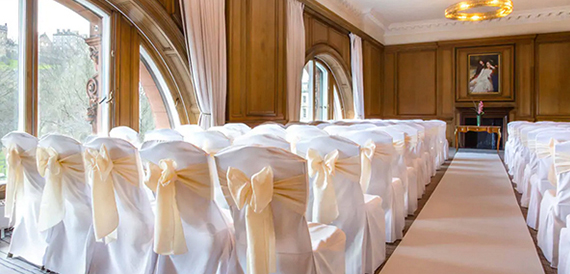 Wedding ceremony seating with cream chair covers and gold sashes