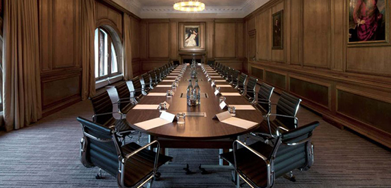 Grand panelled boardroom with a long table and framed oil paintings