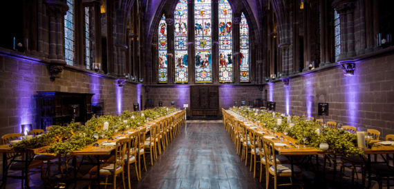 Chester Cathedral's refectory set with long banquet tables beneath stained glass windows