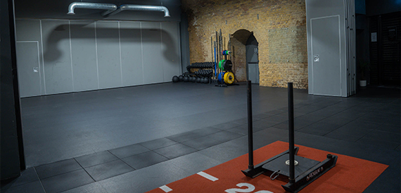 Spacious gym floor with a sled and weights in the corner