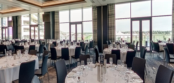 Function room with round tables overlooking the racecourse through glass walls