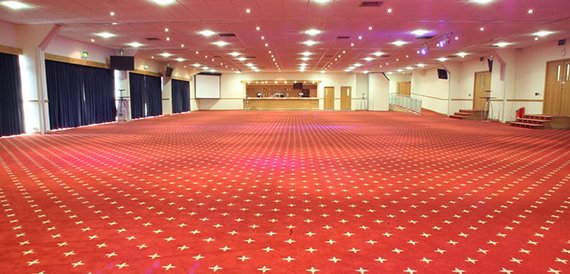 Large empty function room with vivid red patterned carpet, set up ahead of an event