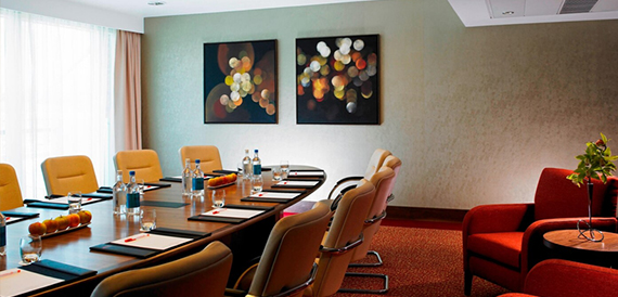 Boardroom meeting room with a long table, cream chairs and abstract wall art