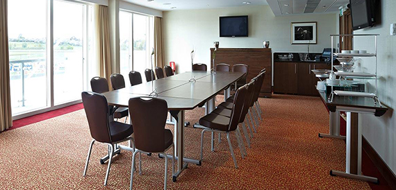 Meeting room with a wall-mounted screen, dark chairs and a buffet counter to the side