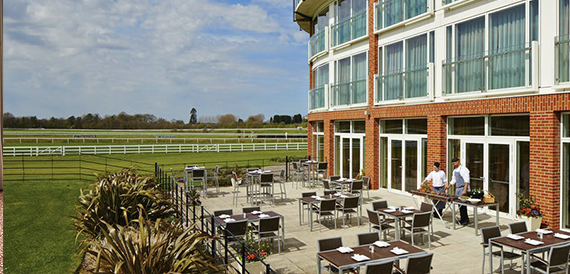 Outdoor terrace dining area overlooking Lingfield Park racecourse with staff preparing tables