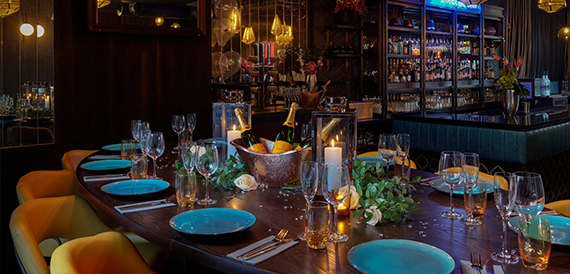 Dining table set with turquoise plates and candles beside the bar