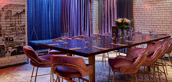 Private dining table with pink chairs, roses and blue and purple curtains