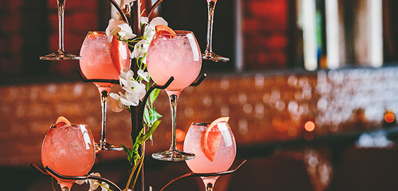 Tiered stand of pink cocktails garnished with grapefruit and flowers