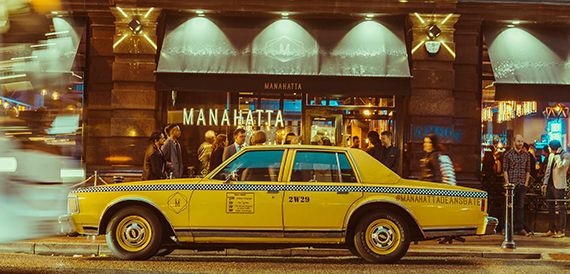 Vintage yellow taxi parked outside the Manahatta entrance at night