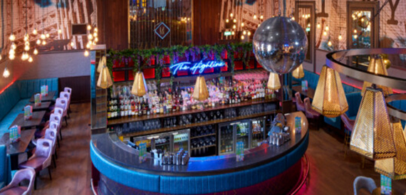 Upper mezzanine bar with a disco ball, neon Highline sign and gold pendant lampshades