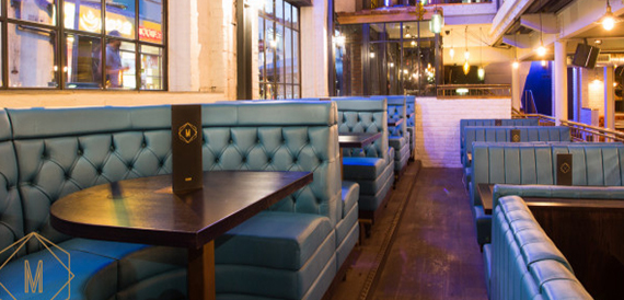 Corridor of teal leather booth seating with dark wood tables