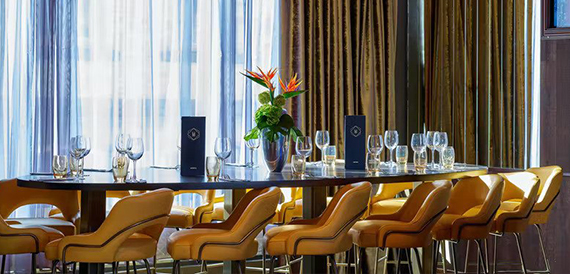 Private dining table with mustard yellow chairs and a bird of paradise flower arrangement