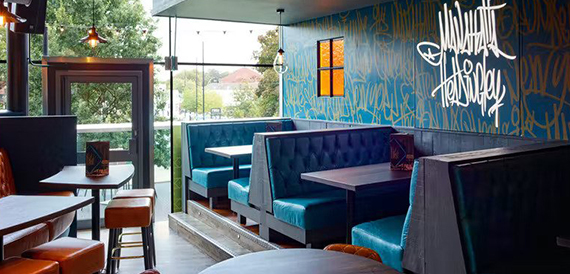 Teal booth seating beneath a graffiti-style Manahatta Headingley wall mural