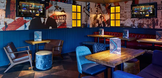 Lounge seating with blue armchairs beneath American-themed wall murals