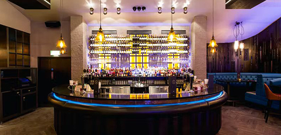 Circular bar counter with an illuminated bottle display and blue neon trim