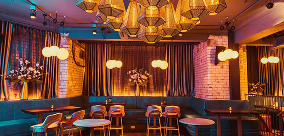 Lounge seating with geometric pendant lamps and velvet stools
