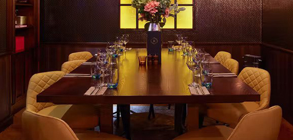 Private dining table with mustard leather chairs and a floral centrepiece against a patterned wall